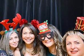 Four guests in holiday hats and antlers at a photo booth, photographed by Dario Hudon