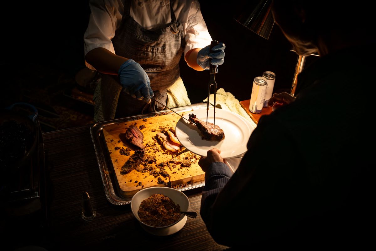 A chef carving at a buffet station in low evening light, photographed by Dario Hudon