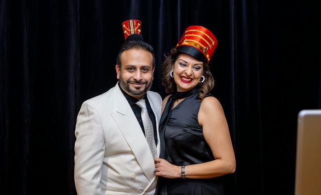Two guests in festive hats at a holiday party photo booth, photographed by Dario Hudon