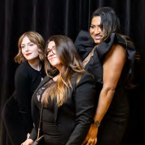 Three guests leaning in together at a photo booth, photographed by Dario Hudon