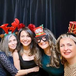 Four guests in holiday hats and antlers at a photo booth, photographed by Dario Hudon