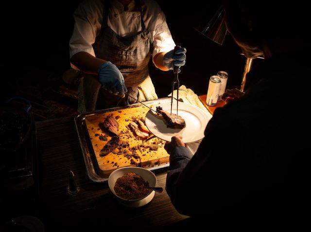 A chef carving at a buffet station in low evening light, photographed by Dario Hudon