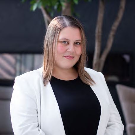 A headshot of a smiling woman in a white blazer, photographed by Dario Hudon