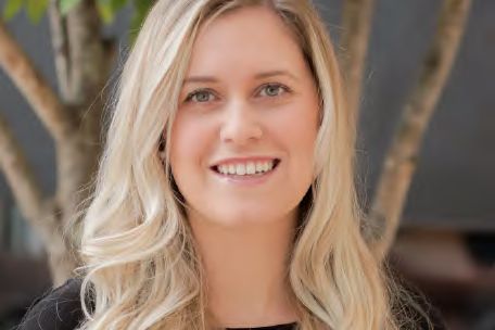 A headshot of a smiling woman with long blonde hair, photographed by Dario Hudon