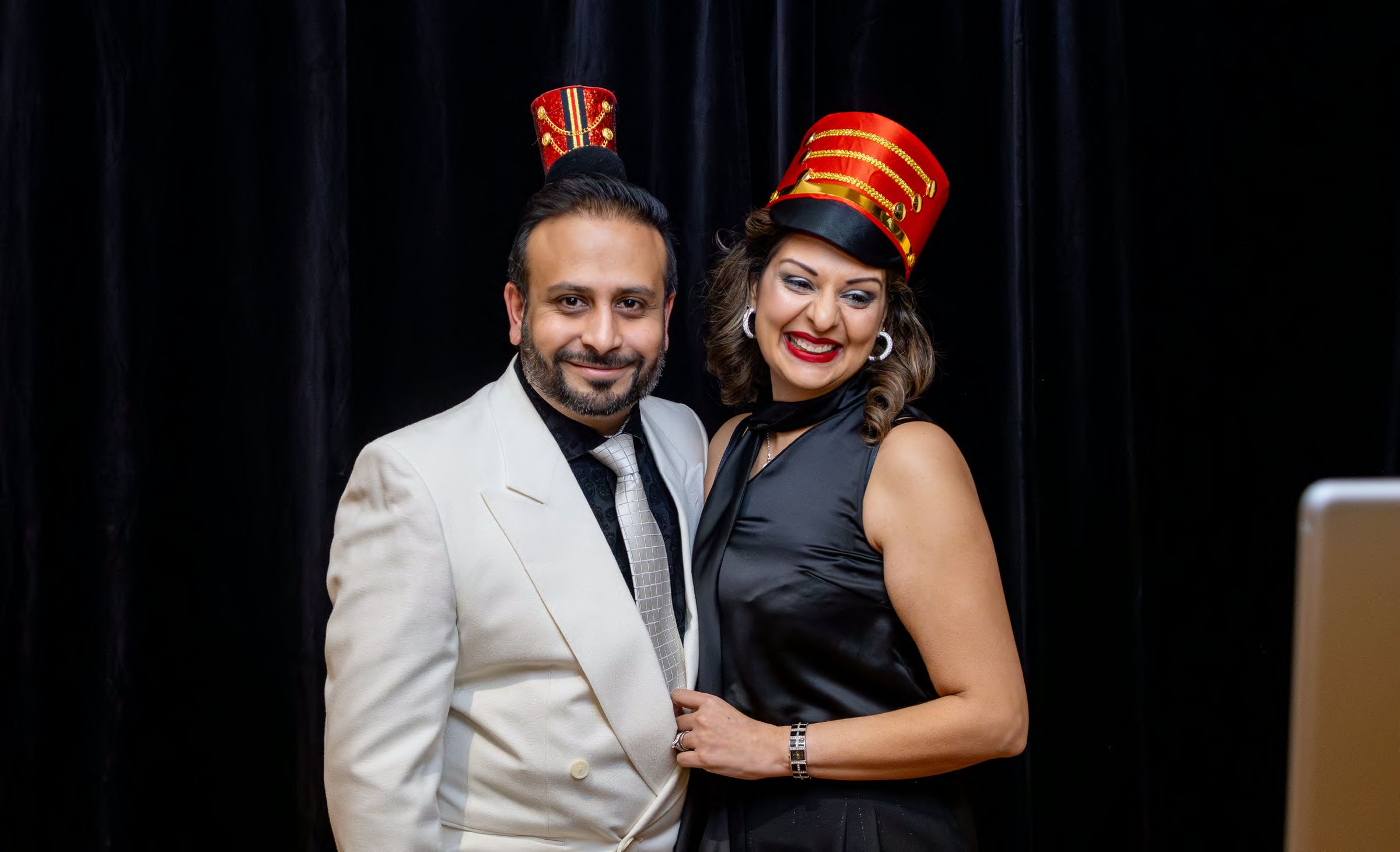 Two guests in festive hats at a holiday party photo booth, photographed by Dario Hudon