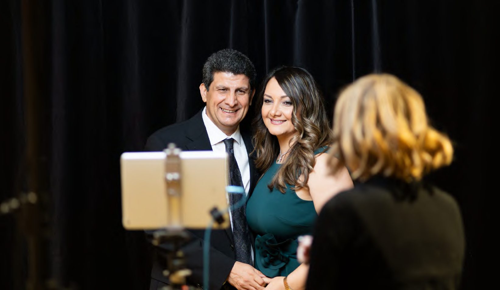 A couple posing at an event photo booth, seen from behind the camera, photographed by Dario Hudon