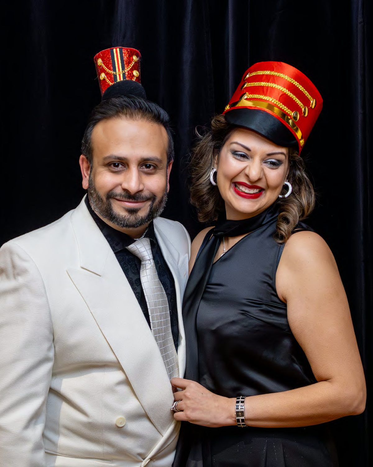 Two guests in festive hats at a holiday party photo booth, photographed by Dario Hudon